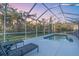 Private screened-in pool with patio, chairs, and lush landscaping beyond at 5001 65Th E Ter, Ellenton, FL 34222