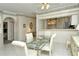 Elegant dining room with glass top table and white chairs, open to kitchen at 5150 Mahogany Run Ave, Sarasota, FL 34241