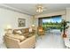 Living room with tan sofas, glass coffee table and view of the patio and golf course at 5150 Mahogany Run Ave, Sarasota, FL 34241