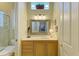 Bathroom vanity with a granite countertop, framed mirror, and stylish faucet, plus a nearby glass door shower at 5304 96Th E St, Bradenton, FL 34211