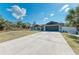 Long concrete driveway leads to an attached garage and a cozy home exterior with a well-maintained lawn at 5551 Allamanda Ave, North Port, FL 34288