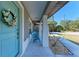 Close-up of the front porch with chairs and decorative flower wreath on the light blue door at 5551 Allamanda Ave, North Port, FL 34288