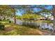 Scenic view of the pond surrounded by trees, lush grass, and landscaping on a sunny day at 5653 Pipers Waite # 26, Sarasota, FL 34235