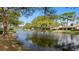 Scenic view of a serene pond surrounded by lush greenery and residences in the distance at 5653 Pipers Waite # 26, Sarasota, FL 34235