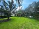 Green grassy backyard with mature trees and water view at 7724 Us Open Loop, Lakewood Ranch, FL 34202