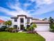 Two-story house featuring a white exterior, brown roof, and lush landscaping at 7724 Us Open Loop, Lakewood Ranch, FL 34202