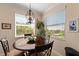 Bright dining area features a wooden table, decorative chandelier, and large windows with plantation shutters at 8403 Grand Estuary Trl # 301, Bradenton, FL 34212