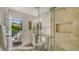 Bathroom featuring tiled glass shower, gray vanity and an exterior door leading to a patio at 1302 Roberts Bay Ln, Sarasota, FL 34242