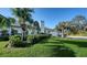 Home's exterior featuring a lush lawn, tropical landscaping, and a paved driveway leading to the garage at 1302 Roberts Bay Ln, Sarasota, FL 34242