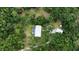 Aerial view of home with circular driveway, detached garage, and private wooded lot at 14018 Pine Woods E Ln, Sarasota, FL 34240