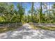 Long driveway leading to a home with white fence and lush trees at 14018 Pine Woods E Ln, Sarasota, FL 34240