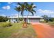 Single-story home with gray exterior, palm trees, and a red driveway at 157 Da Vinci Dr, Nokomis, FL 34275