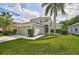 Inviting home exterior with a lush green lawn, mature landscaping, and an arched entryway at 1671 Mellon Way, Sarasota, FL 34232