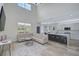 Open-concept living room with a modern sectional, adjacent to an island kitchen and soaring ceilings at 1671 Mellon Way, Sarasota, FL 34232