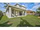 Wide shot of the covered patio with chairs and grill, and expansive backyard at 1671 Mellon Way, Sarasota, FL 34232