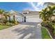 Beautiful single-Gathering home featuring a three-car garage, lush landscaping, and a brick driveway at 16730 Collingtree Xing, Lakewood Ranch, FL 34202