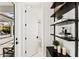 Hallway featuring a door that leads to a bathroom with black shelves on the wall at 16730 Collingtree Xing, Lakewood Ranch, FL 34202