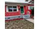 Close-up of a quaint front porch with red exterior, white railing, and a green front door at 1711 41St S St, St Petersburg, FL 33711