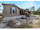 Exterior view of a charming home with a long front porch, trees and gravel landscaping at 17555 Lake Worth Blvd, Port Charlotte, FL 33948