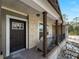 Welcoming front porch with stone detailing, dark wooden columns, and a black metal railing at 17555 Lake Worth Blvd, Port Charlotte, FL 33948