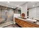 Bathroom featuring double sinks, floating vanity, and a walk-in shower with natural stone and pebble floor at 300 S Pineapple Ave # 802, Sarasota, FL 34236