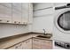 Bright laundry room with light wood cabinets, a sink, and modern appliances at 300 S Pineapple Ave # 802, Sarasota, FL 34236