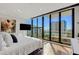 Main bedroom featuring large windows, a glass balcony and a mounted TV with modern décor at 300 S Pineapple Ave # 802, Sarasota, FL 34236