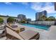 Community pool surrounded by tile patio, lounge chairs, and nearby high-rise buildings at 300 S Pineapple Ave # 802, Sarasota, FL 34236