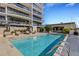 Community pool featuring crystal clear water, lounge chairs, and building with wrap-around balconies in the background at 300 S Pineapple Ave # 802, Sarasota, FL 34236