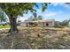 Quaint single-story home with a lawn featuring mature trees under a blue sky at 3718 61St St, Bradenton, FL 34209