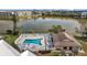 Aerial view of a community pool and clubhouse set beside a scenic lake and dock at 4126 Heron Way # B113, Bradenton, FL 34205