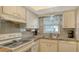 Kitchen featuring white cabinets, gray backsplash, and stainless steel sink and appliances at 4616 Park Acres Dr, Bradenton, FL 34207