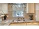 Kitchen featuring white cabinets, gray backsplash, stainless sink, and a window with a view at 4616 Park Acres Dr, Bradenton, FL 34207