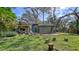 Back exterior of home with wooden deck and lush lawn with mature trees and foliage at 5180 Meldon Cir, Sarasota, FL 34232