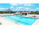 Sparkling community pool with lounge chairs, umbrellas, and clubhouse in a lush, tropical setting at 6939 W Country Club N Dr # 158, Sarasota, FL 34243