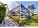 A backyard patio area under a screened in lanai, surrounded by mature landscaping at 8729 52Nd E Dr, Bradenton, FL 34211