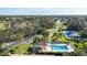 Aerial view of the pool, tennis court, road, and trees in the neighborhood at 8755 Olde Hickory Ave # 7302, Sarasota, FL 34238