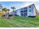 Well-maintained building with lush green lawn, palm trees, and screened lanais at 8755 Olde Hickory Ave # 7302, Sarasota, FL 34238