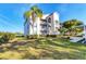 Exterior view of condo complex building with a well-manicured lawn, landscaping, and a palm tree at 8755 Olde Hickory Ave # 7302, Sarasota, FL 34238