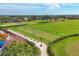 Scenic aerial of a golf course featuring a driving range with lush green fairways and palm tree lined streets at 8755 Olde Hickory Ave # 7302, Sarasota, FL 34238