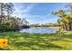 Serene lake view surrounded by lush greenery and mature trees, yellow flowers in foreground at 8755 Olde Hickory Ave # 7302, Sarasota, FL 34238