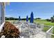 Outdoor patio area with tables, umbrellas, and chairs overlooking a golf course on a sunny day at 8755 Olde Hickory Ave # 7302, Sarasota, FL 34238