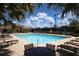 Community pool with lounge chairs and table under a sunny, partly cloudy sky at 8755 Olde Hickory Ave # 7302, Sarasota, FL 34238