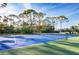 Outdoor tennis court with a vibrant blue surface and lush green surroundings at 8755 Olde Hickory Ave # 7302, Sarasota, FL 34238