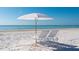 Serene beach view with white sand, clear blue water, and beach chairs with umbrella at 1035 Seaside Dr # 503, Sarasota, FL 34242