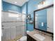 Bright blue bathroom featuring a walk-in shower and modern vanity with a granite countertop at 13922 Old Creek Ct, Parrish, FL 34219