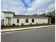 Side view of a white house with clean lines, trimmed bushes, and blue skies in the background at 1790 White Orchid Ct, Sarasota, FL 34235