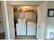 Laundry room with front loading washer and dryer, shelving, and white bi-fold doors at 1790 White Orchid Ct, Sarasota, FL 34235