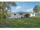 View of the house from the backyard with plenty of green space and some trees at 2079 Pellam Blvd, Port Charlotte, FL 33948