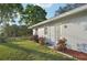 Side view of a house with a well-maintained lawn, decorative flowers and a fenced yard at 2079 Pellam Blvd, Port Charlotte, FL 33948